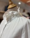 Chemisier blanc avec un col volanté à bouton doré
