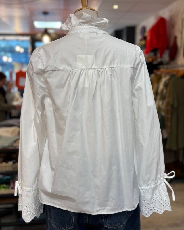 Chemisier blanc avec un col volanté à bouton doré