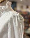 Chemisier blanc avec un col volanté à bouton doré