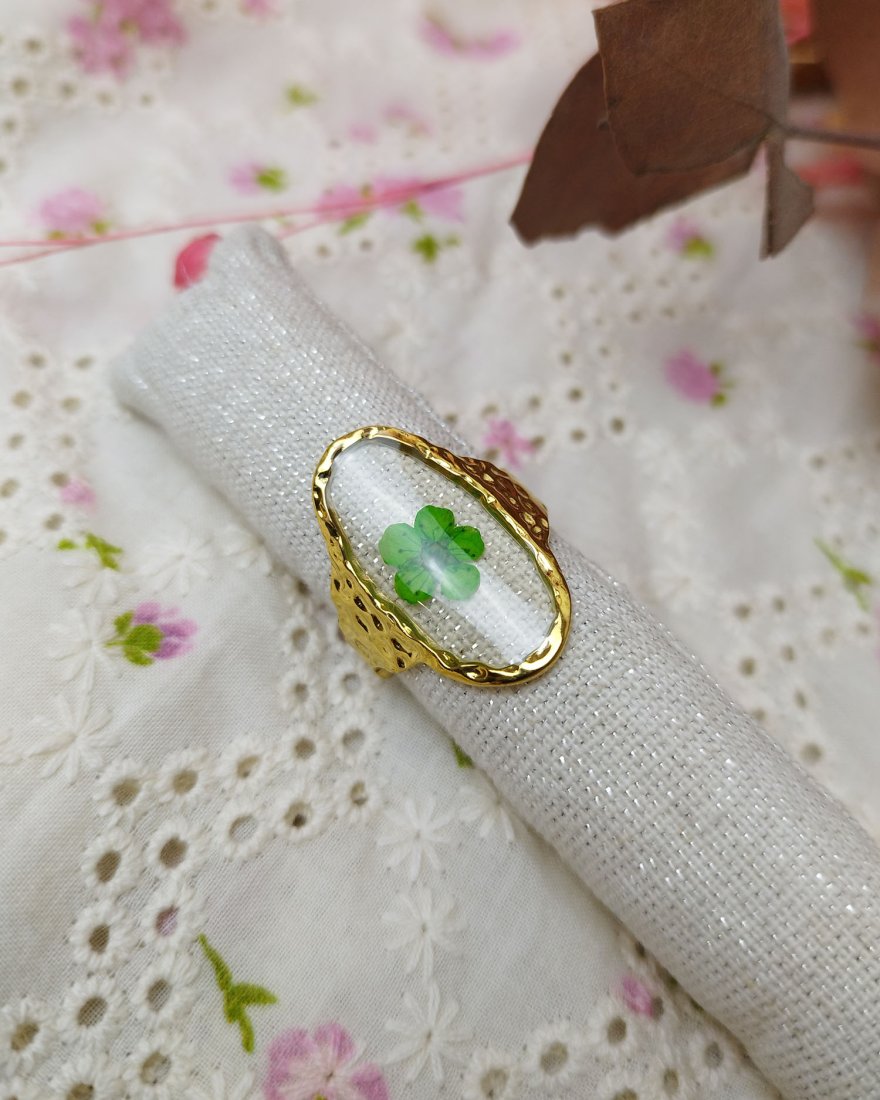Bague ovale transparente avec une fleur séchée verte