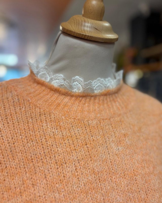 Pull en maille orange avec des finitions en dentelle blanche