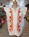 Chemisier blanc sans manches avec des broderies fleuries